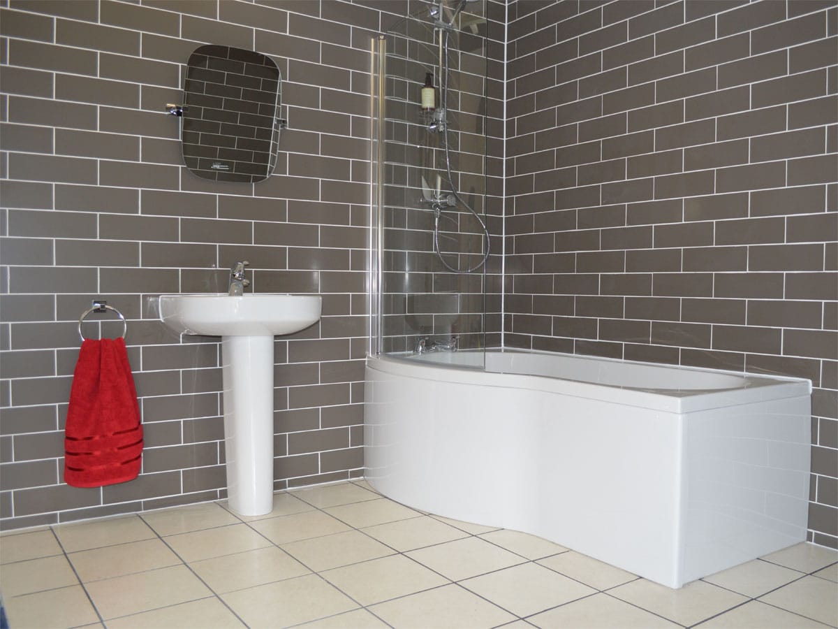 fully tiled bathroom with a shower bath and basin & pedestal